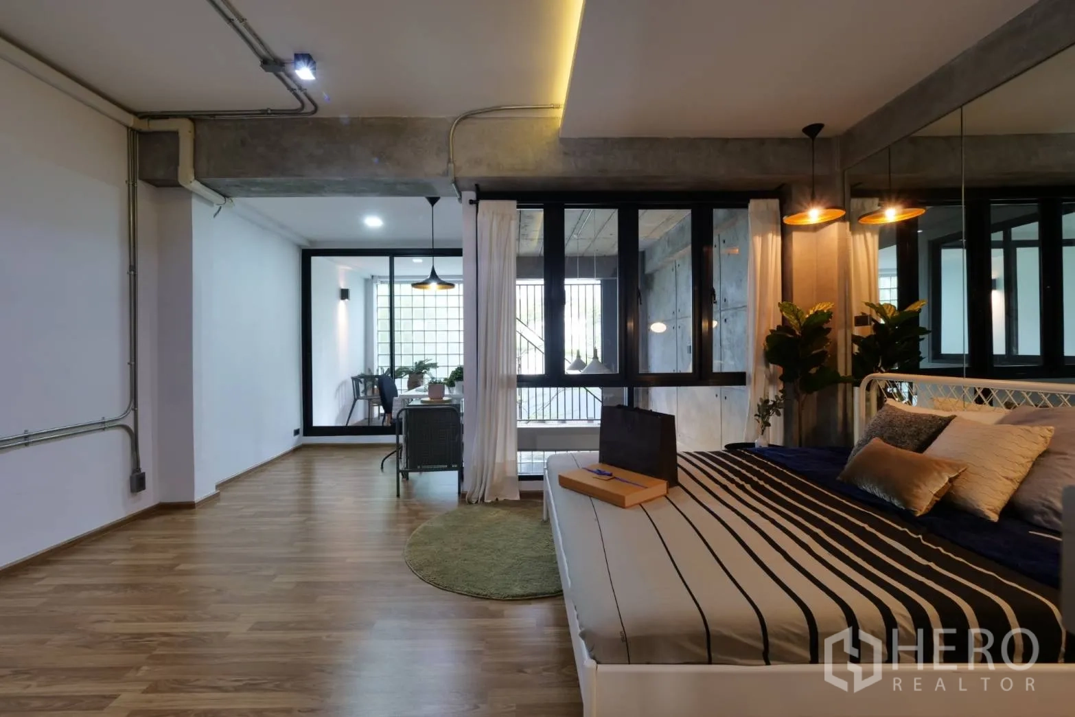 联排别墅 出租在Khlong Toei, Bangkok - 工作室式卧室，条纹床品、镜面墙与玻璃书房角。
