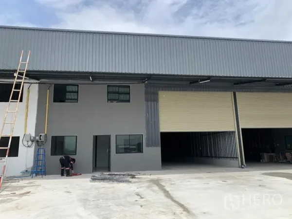 货栈 出租在Khlong Luang, Pathum Thani - 新建小型工厂/仓库外观，带两层办公室和大型卷帘门，前方混凝土场地