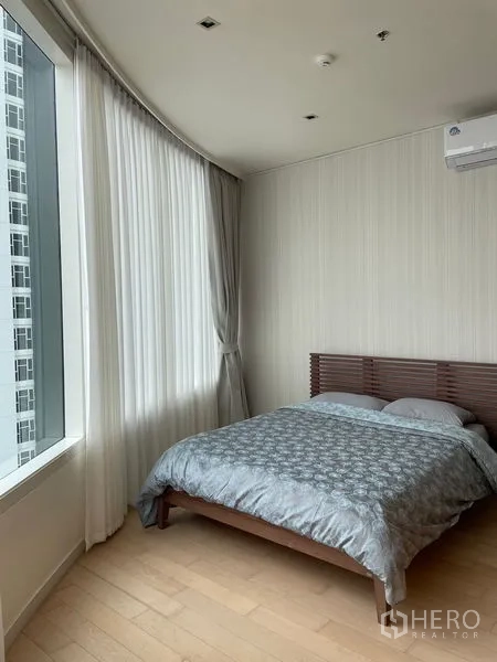 公寓 出租在Watthana, Bangkok - 主卧配大窗、空调与木质床架，采光充足。