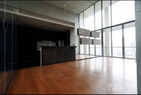 Condominium for rent in Sathon, Bangkok - Open-plan living and dining space with a kitchen island and full-height windows flooding the room with light.
