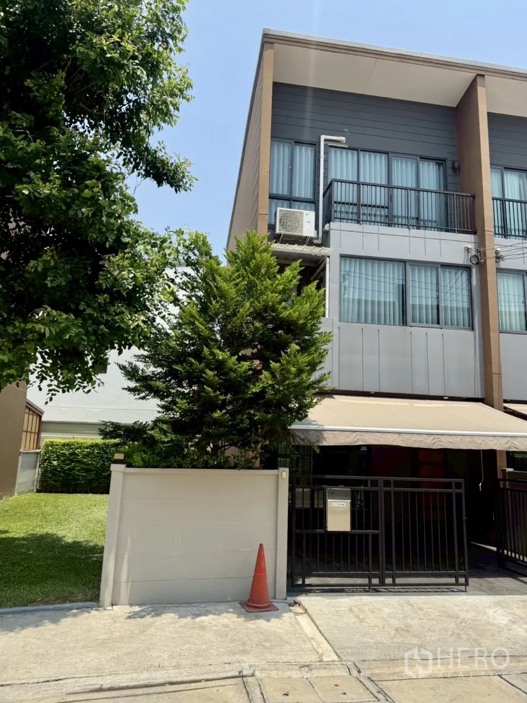 Townhouse for rent in Prawet, Bangkok - Modern townhouse exterior with gated entrance, awning, and mature trees.
