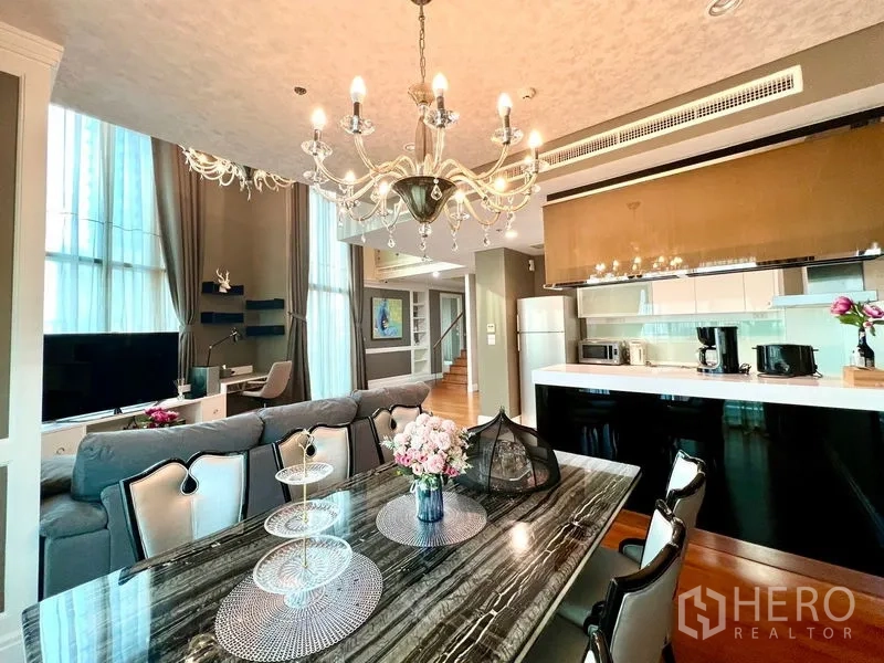 Condominium for rent in Khlong Toei, Bangkok - Open-plan dining and kitchen with marble table and statement lighting.