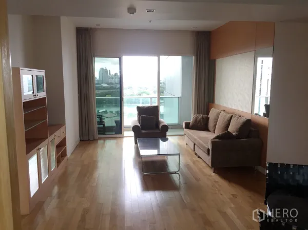 Condominium for rent in Khlong Toei, Bangkok - Spacious living room with hardwood floors, sofa set, media cabinet and balcony overlooking the skyline.
