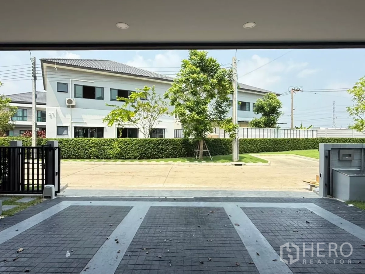 独立式住宅 出租在Bang Phli, Samut Prakan - 从有顶车库望向小区内道路与绿篱，前方无遮挡