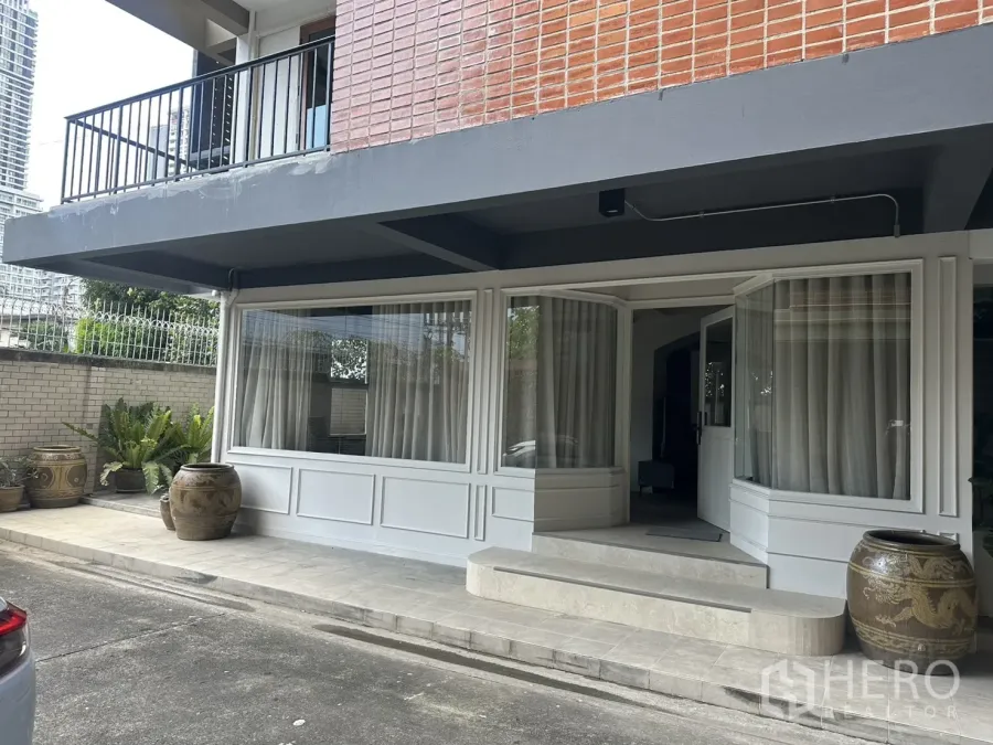 พื้นที่ขายของ for rent in Watthana, Bangkok - ด้านหน้าระดับถนนพร้อมกระจกบานใหญ่ บันไดทางเข้า และโอ่งปลูกต้นไม้.