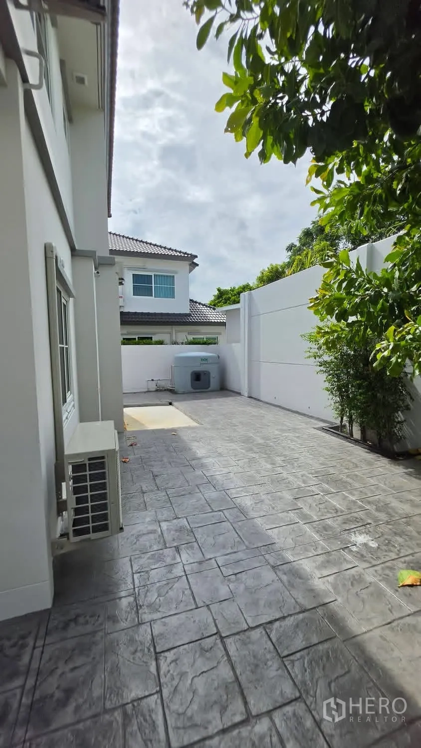 独栋房屋 for rent in Bang Phli, Samut Prakan - 后院大面积铺装庭院，围墙私密，树荫与水箱可见。