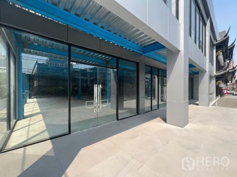 Retail Space for rent in Huai Khwang, Bangkok - Ground-floor glass storefront with double doors beneath a blue steel canopy at a contemporary retail block.