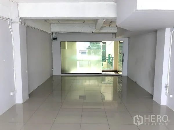 Office Space for rent in Khlong Toei, Bangkok - Open-plan office interior with shiny tiled flooring, frosted glass panel and doorway to a balcony corridor.