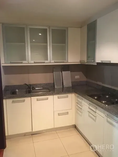 公寓 出租或出售在Watthana, Bangkok - U 型厨房，白色橱柜、花岗岩台面、双水槽与内置灶台。