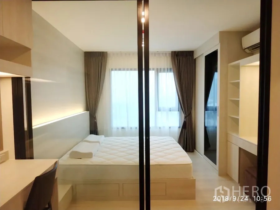 คอนโด ให้เช่าในHuai Khwang, Bangkok - ห้องนอนสว่างกั้นกระจก เตียงควีน บิ้วท์อินโต๊ะทำงาน และหน้าต่างผ้าม่านทึบแสงสูงจรดเพดาน.