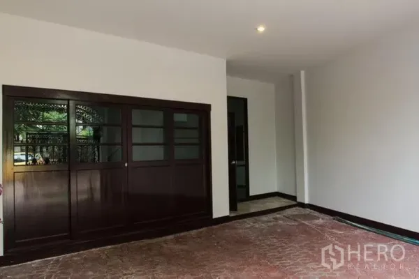 联排别墅 出租在Khlong Toei, Bangkok - 有顶车位与入口区，深色木质推拉门与砖纹地面。