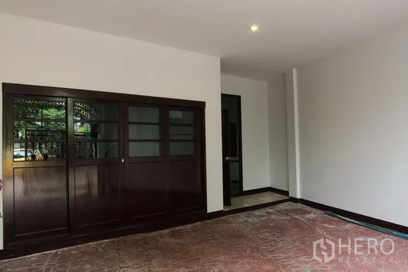 联排别墅 出租在Khlong Toei, Bangkok - 有顶车位与入口区，深色木质推拉门与砖纹地面。