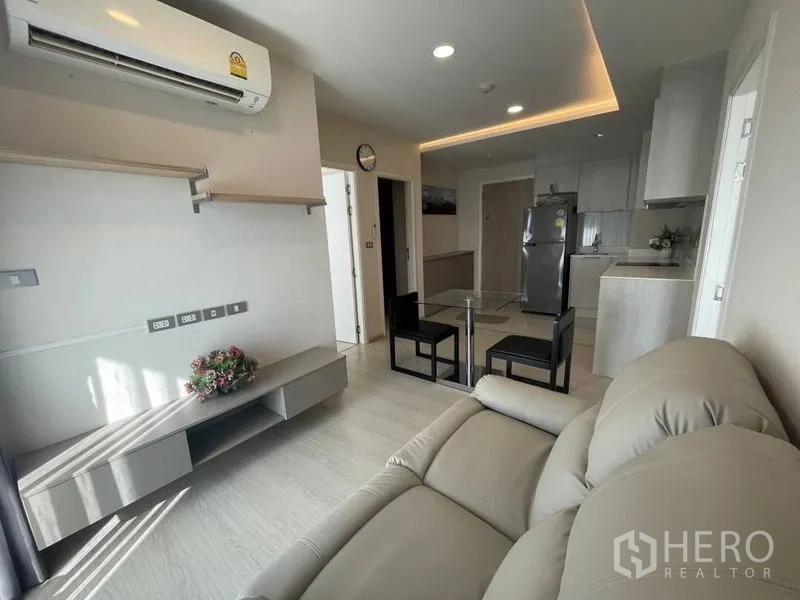 Condominium for rent in Khlong Toei, Bangkok - View from sofa to kitchen with built-in cabinets, stainless fridge, and glass dining set.