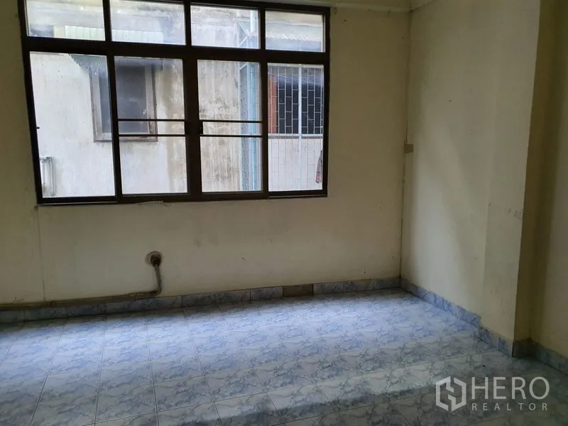 店屋 出租在Bang Rak, Bangkok - 带大窗的房间，窗外朝向相邻建筑，地面为瓷砖。