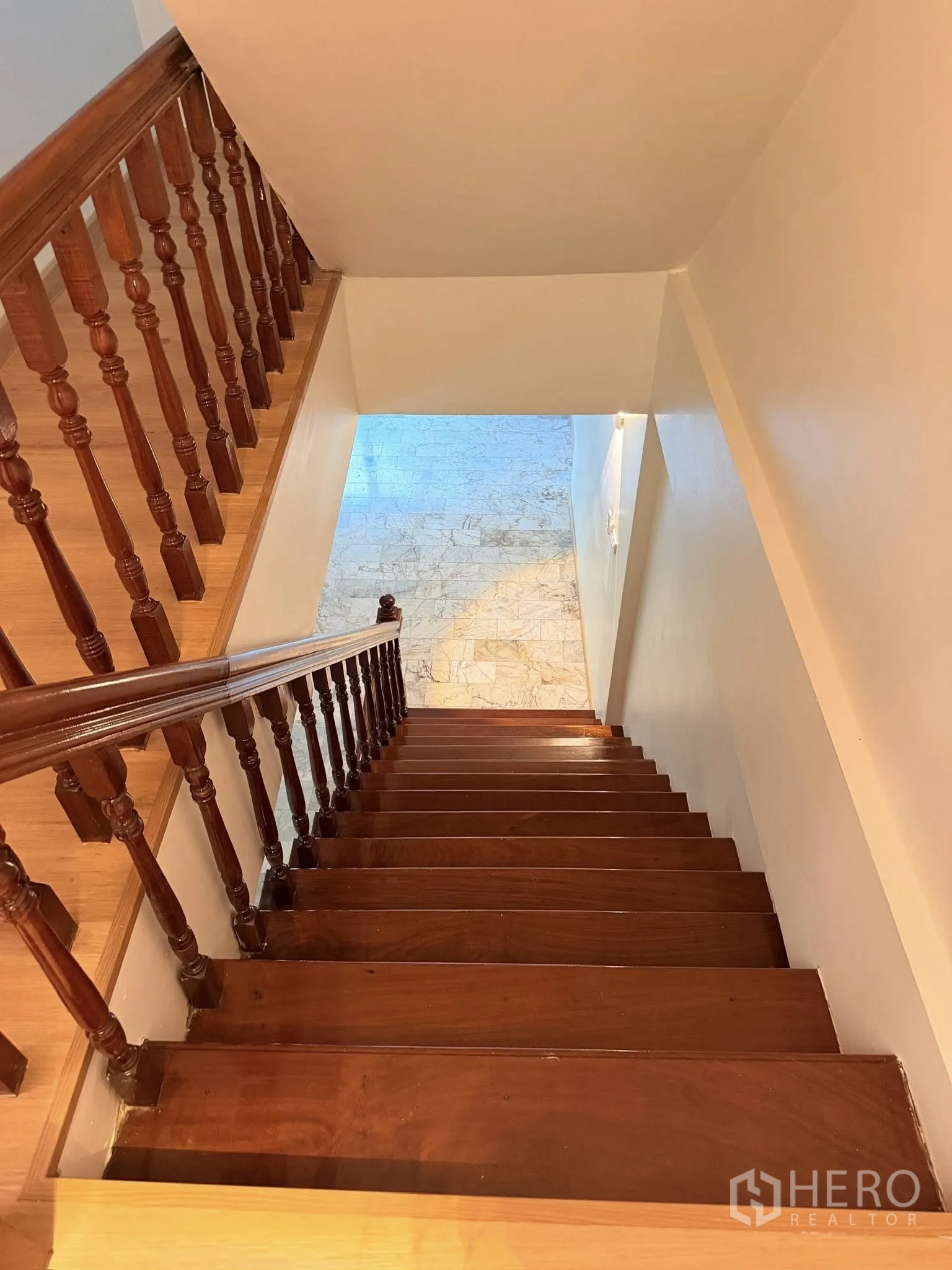 Townhouse for rent or sale in Yan Nawa, Bangkok - View down the wooden staircase to the marble-floored ground level.