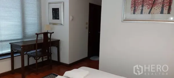 Condominium for rent in Sathon, Bangkok - Bedroom corner with a writing desk by the window and framed artwork on light walls.