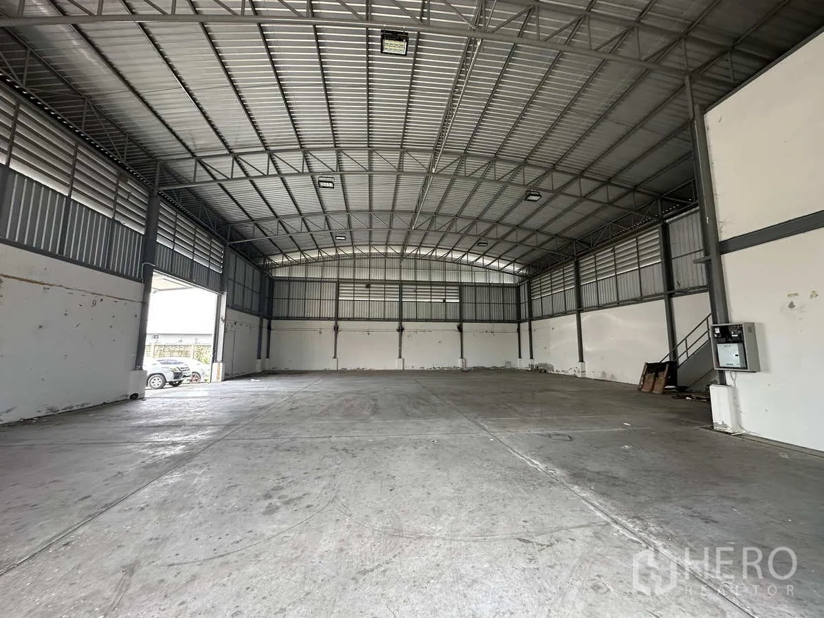 โรงงาน ให้เช่าในPathum Thani - มุมมองภายในไปยังผนังด้านหลัง มีประตูทางออกด้านข้างและบันไดเหล็ก