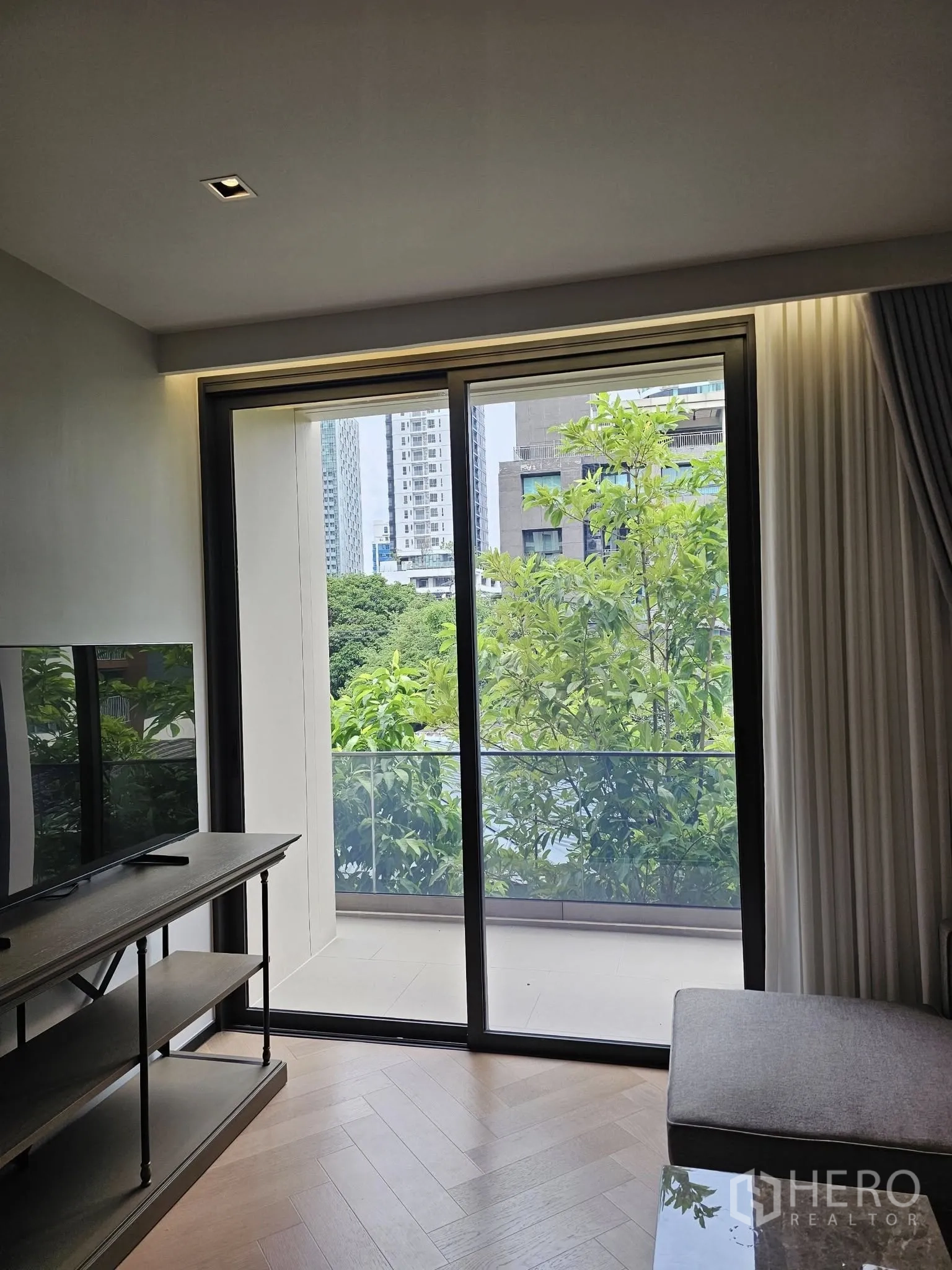 คอนโด ให้เช่าในWatthana, Bangkok - พื้นที่นั่งเล่นเปิดสู่ระเบียงส่วนตัว วิวร่มไม้และตึกเมือง