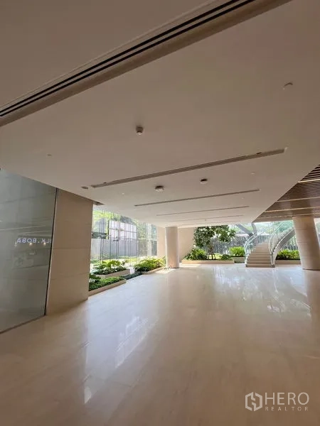 Retail Space for rent - Open-plan entrance hall with glossy tile flooring, glass wall frontage, indoor greenery and staircase access.
