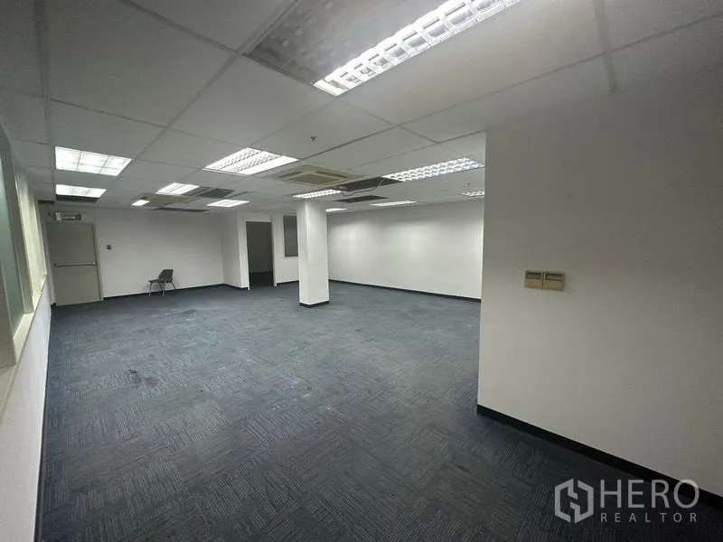 办公空间 出租在Khlong Toei, Bangkok - 开放式工作区，蓝色地毯，网格灯吊顶与立柱。
