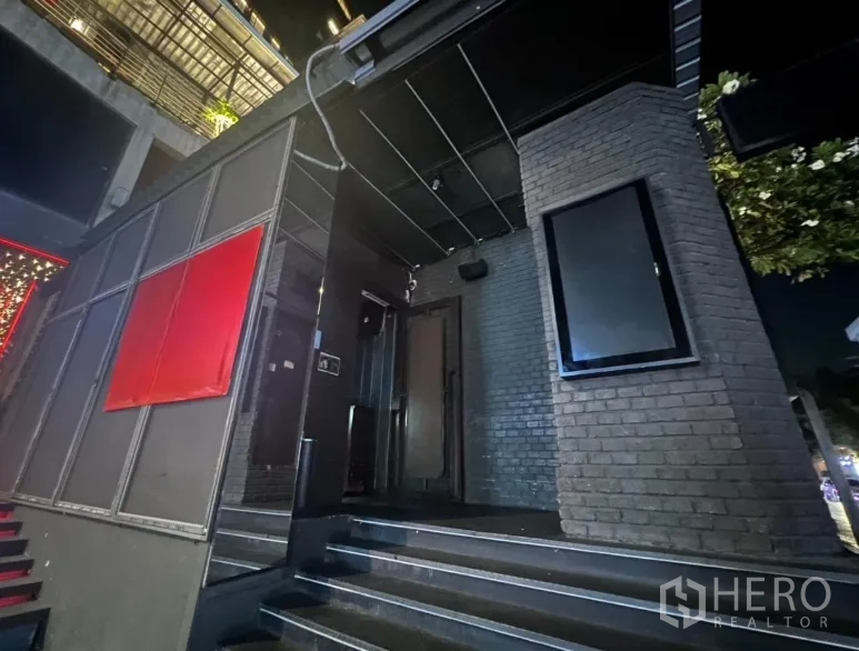 Retail Space for rent in Bangkok - Nighttime exterior of dark brick retail unit with canopy and steps.