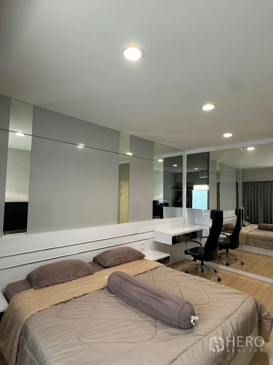 Townhouse for rent in Suan Luang, Bangkok - Bedroom view showing mirrored wall, built-in headboard and study desk with chairs.