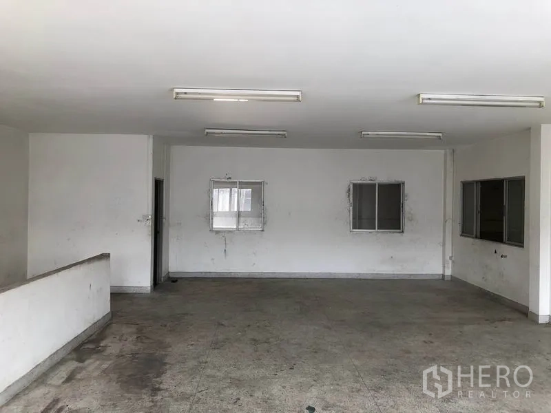 Factory for rent in Nonthaburi - Open-plan office room with fluorescent lighting and sliding windows.