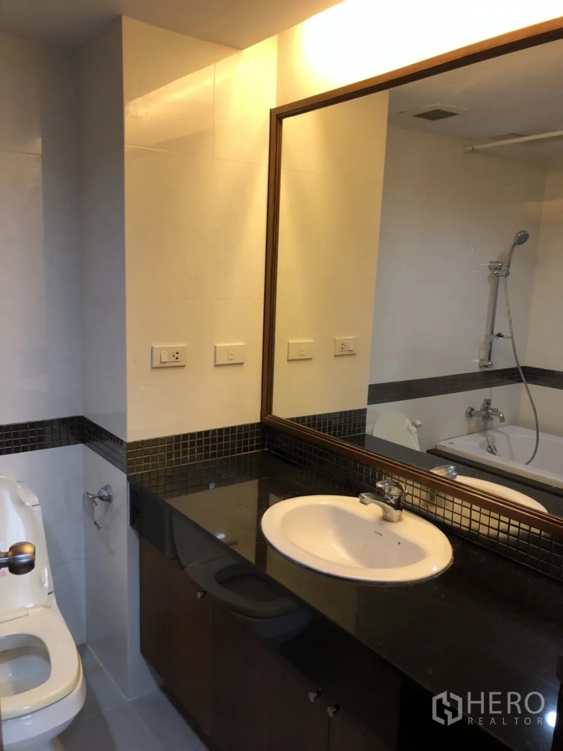 Condominium for rent in Watthana, Bangkok - Bathroom with long black granite counter, sink and bathtub.