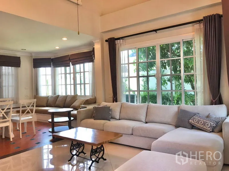 บ้าน ให้เช่าในMueang Samut Prakan, Samut Prakan - ห้องนั่งเล่นสว่างด้วยหน้าต่างบานใหญ่ โซฟาเข้ามุม โต๊ะกลาง และผ้าม่าน
