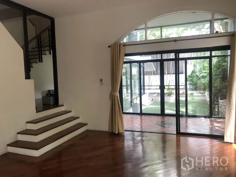 Detached House for rent in Bang Rak, Bangkok - Bright living area with wooden floors and sliding glass doors opening to the garden.