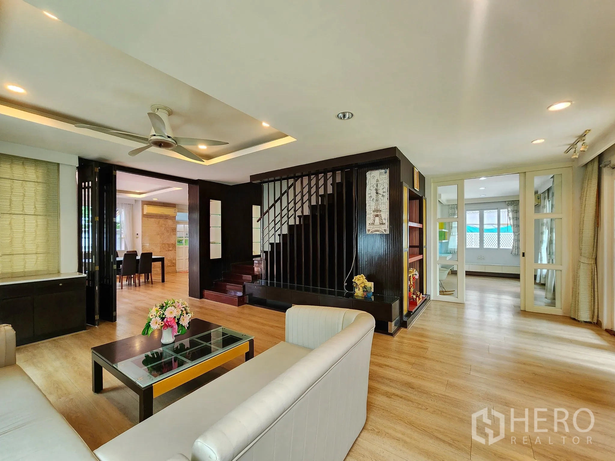 Detached House for rent in Bang Kapi, Bangkok - Open-plan lounge with dark wood staircase and adjoining dining space.