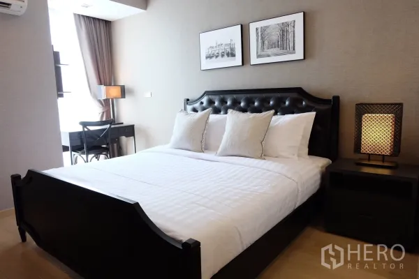 Condominium for rent in Watthana, Bangkok - Master bedroom featuring a tufted headboard bed, bedside lamp, and work desk by the window.