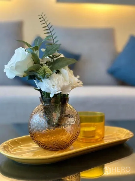 Condominium for rent in Bang Rak, Bangkok - Close-up of decorative flower vase and tumbler on a yellow tray atop a glass coffee table.