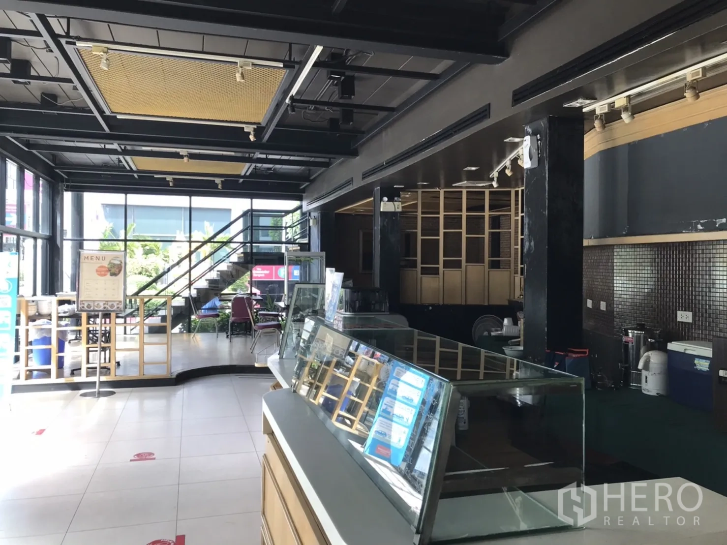 Retail Space for rent in Khlong Toei, Bangkok - Ground-floor retail hall with display counters, staircase to upper level and wide glazing.