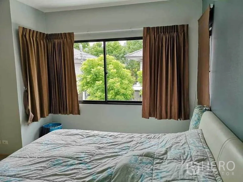 บ้าน ขายในBang Phli, Samut Prakan - ห้องนอนอบอุ่น หน้าต่างมุมกว้าง ผ้าม่านสีน้ำตาล มองเห็นต้นไม้สีเขียว
