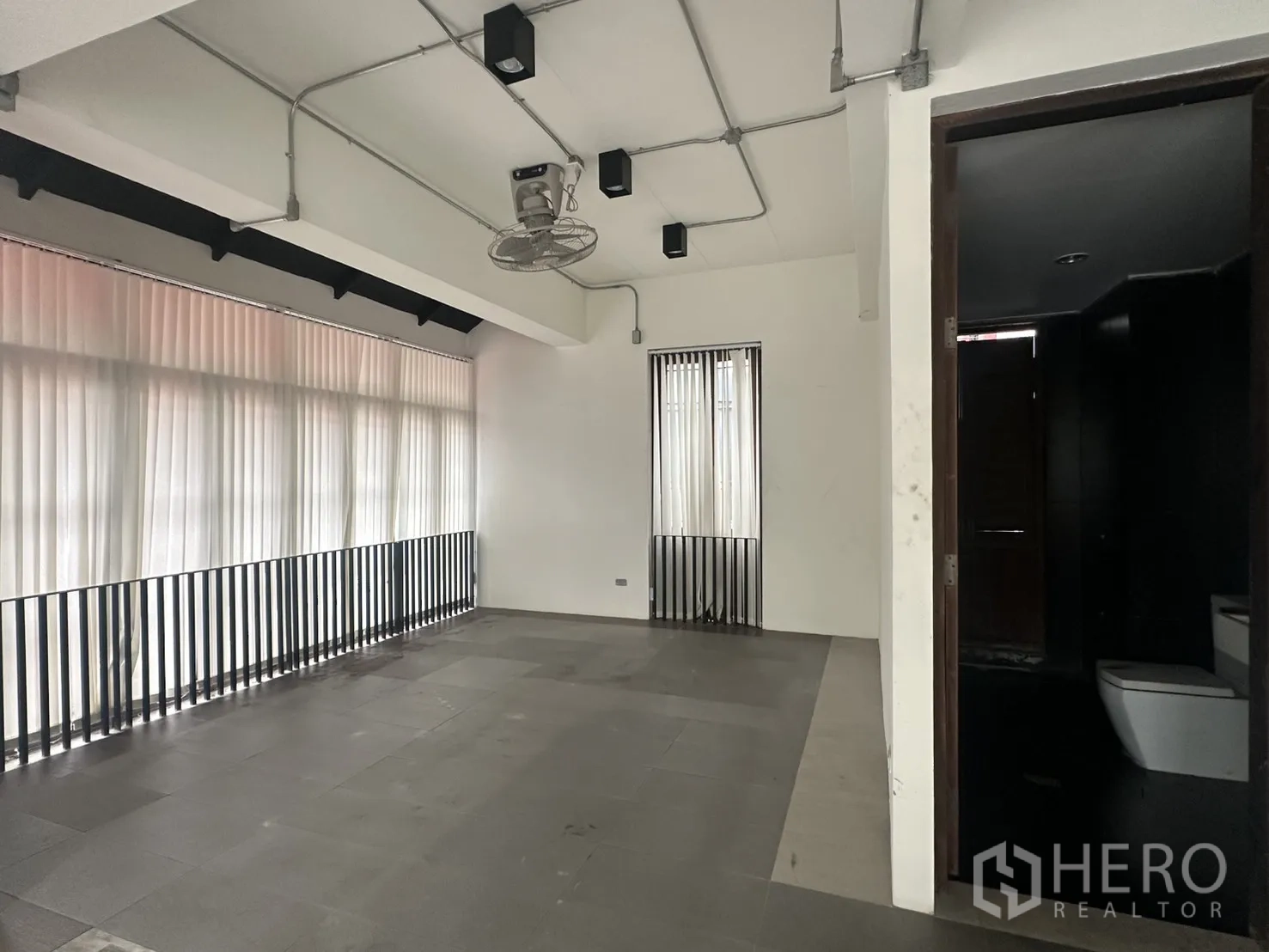 带办公室的家 for rent in Pathum Wan, Bangkok - 宽敞房间带大窗与通往卫浴的门，工业风吊灯可见。