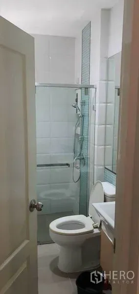 Detached House for sale in Khan Na Yao, Bangkok - Modern bathroom with white tiles, glass-enclosed shower, vanity and toilet in a detached house in Khan Na Yao, Bangkok.
