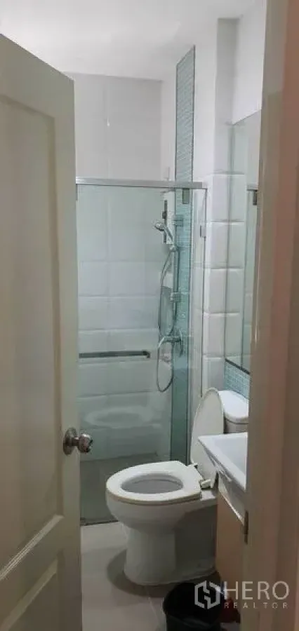 Detached House for sale in Khan Na Yao, Bangkok - Modern bathroom with white tiles, glass-enclosed shower, vanity and toilet in a detached house in Khan Na Yao, Bangkok.