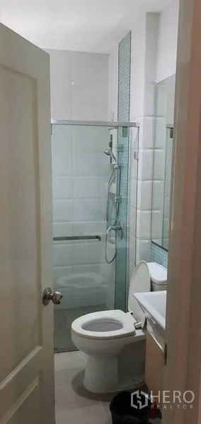 Detached House for sale in Khan Na Yao, Bangkok - Modern bathroom with white tiles, glass-enclosed shower, vanity and toilet in a detached house in Khan Na Yao, Bangkok.