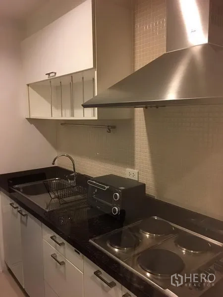 Condominium for rent in Khlong Toei, Bangkok - Compact separate kitchen with granite countertop, electric hob, sink and range hood.