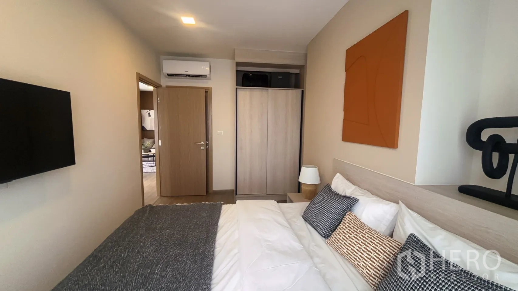 公寓 for rent in Watthana, Bangkok - 卧室视角可见壁挂电视、推拉门衣柜、床头灯与空调。
