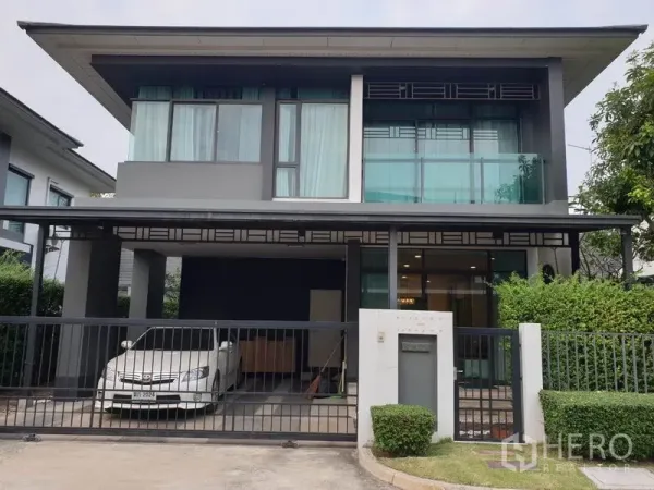 独立式住宅 出租在Bang Kapi, Bangkok - 现代两层独栋住宅的正立面，带大门、遮棚车位与大面积玻璃窗。