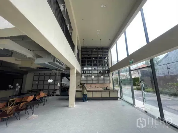 零售空间 出租在Phra Khanong, Bangkok - 挑高零售室内，落地玻璃、服务吧台与高层展示架，位于曼谷帕卡农。