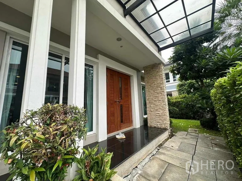 独立式住宅 出售在Saphan Sung, Bangkok - 带顶门廊，双开木门与石材立柱，旁连花园。