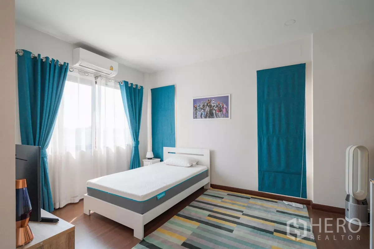Detached House for sale in Saphan Sung, Bangkok - Second bedroom with single bed, patterned rug and teal drapes.