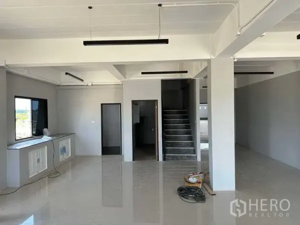 Factory for sale in Khlong Luang, Pathum Thani - Ground-floor office area with tiled floor, staircase, windows and linear LED lighting.