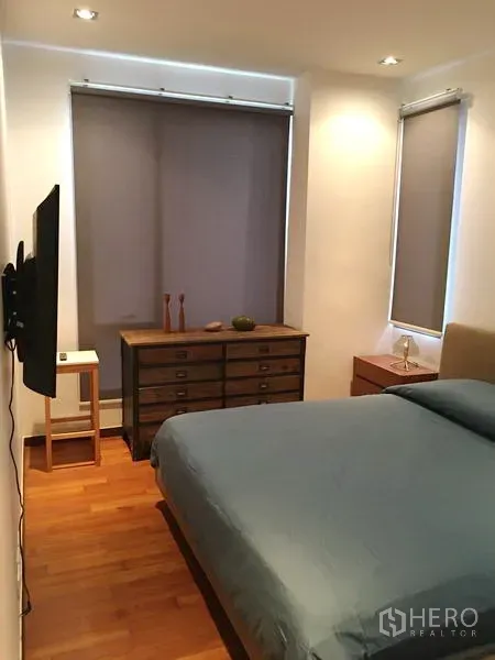 Condominium for rent or sale in Khlong Toei, Bangkok - Second bedroom with double bed, wall-mounted TV, dresser and roller blinds.
