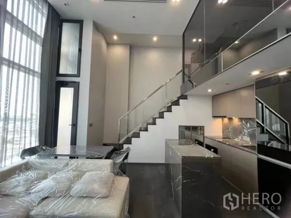 Condominium for rent in Ratchathewi, Bangkok - Bright living–dining space with sofa set, island kitchen, and stairs leading to the loft.
