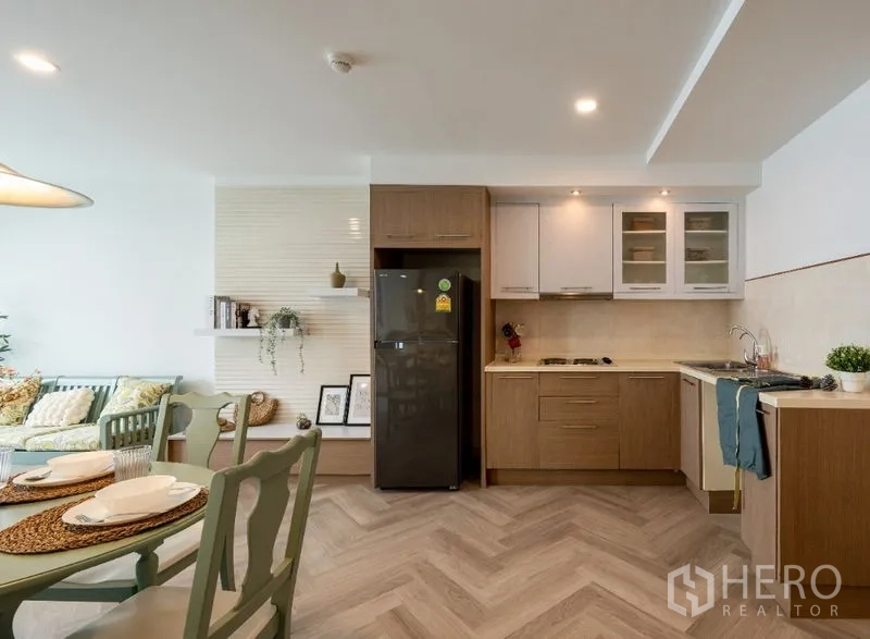 公寓 出售在Watthana, Bangkok - 现代L形厨房，上下柜、黑色冰箱与嵌入式炉灶。