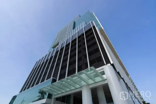 Office Space for rent in Sathon, Bangkok - Modern glass office tower in Sathon viewed from the street against a blue sky.